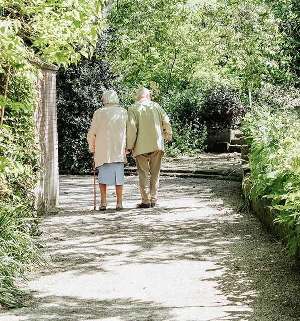Elderly couple walking together on a garden path